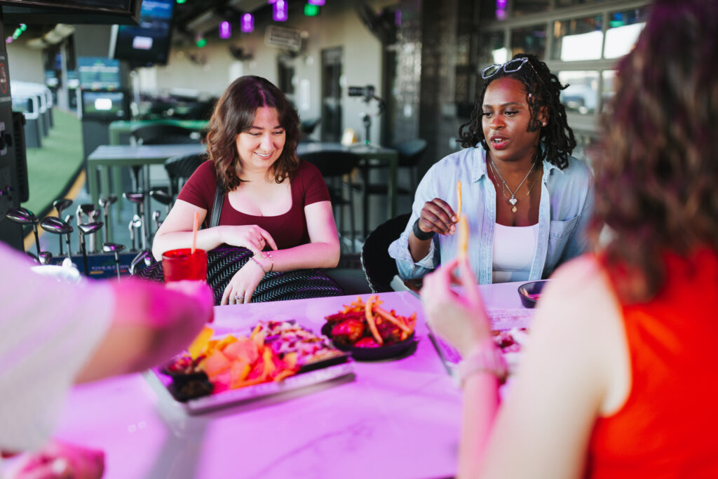 Group of friends enjoying appetizers at a sports bar and golf entertainment venue for a kids birthday party in New Orleans.